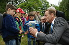 Ein Junge zeigt einem Mann im Anzug zum Tag der kleinen Forscher 2012 sein Klimaglas.