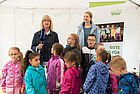 Kinder und eine Fernsehmoderatorin mit Mikrophon zum Tag der kleinen Forscher in Rostock